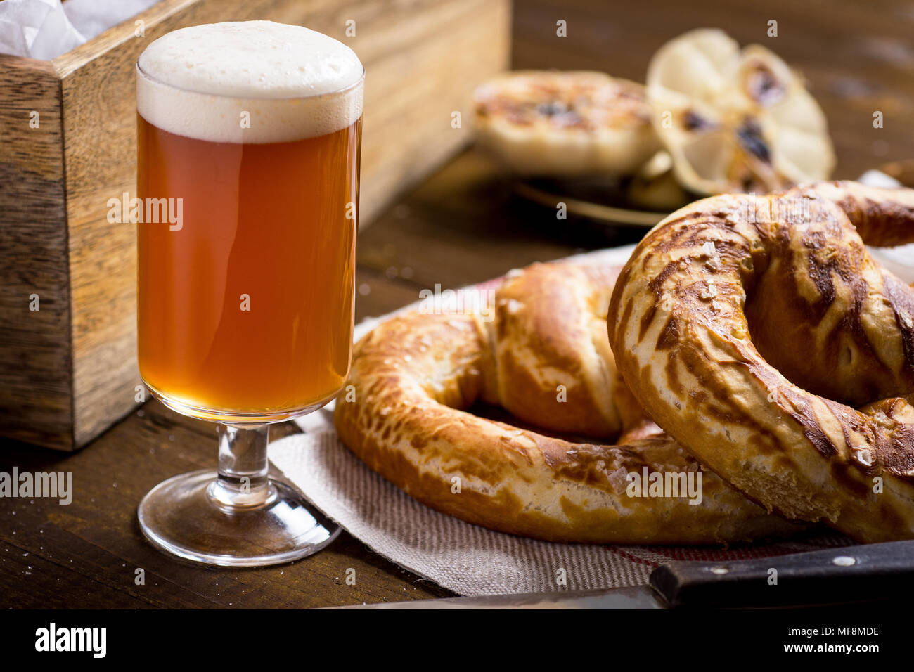 In casa Pretzel con sale marino e bicchiere di birra su tavola in legno rustico Foto Stock