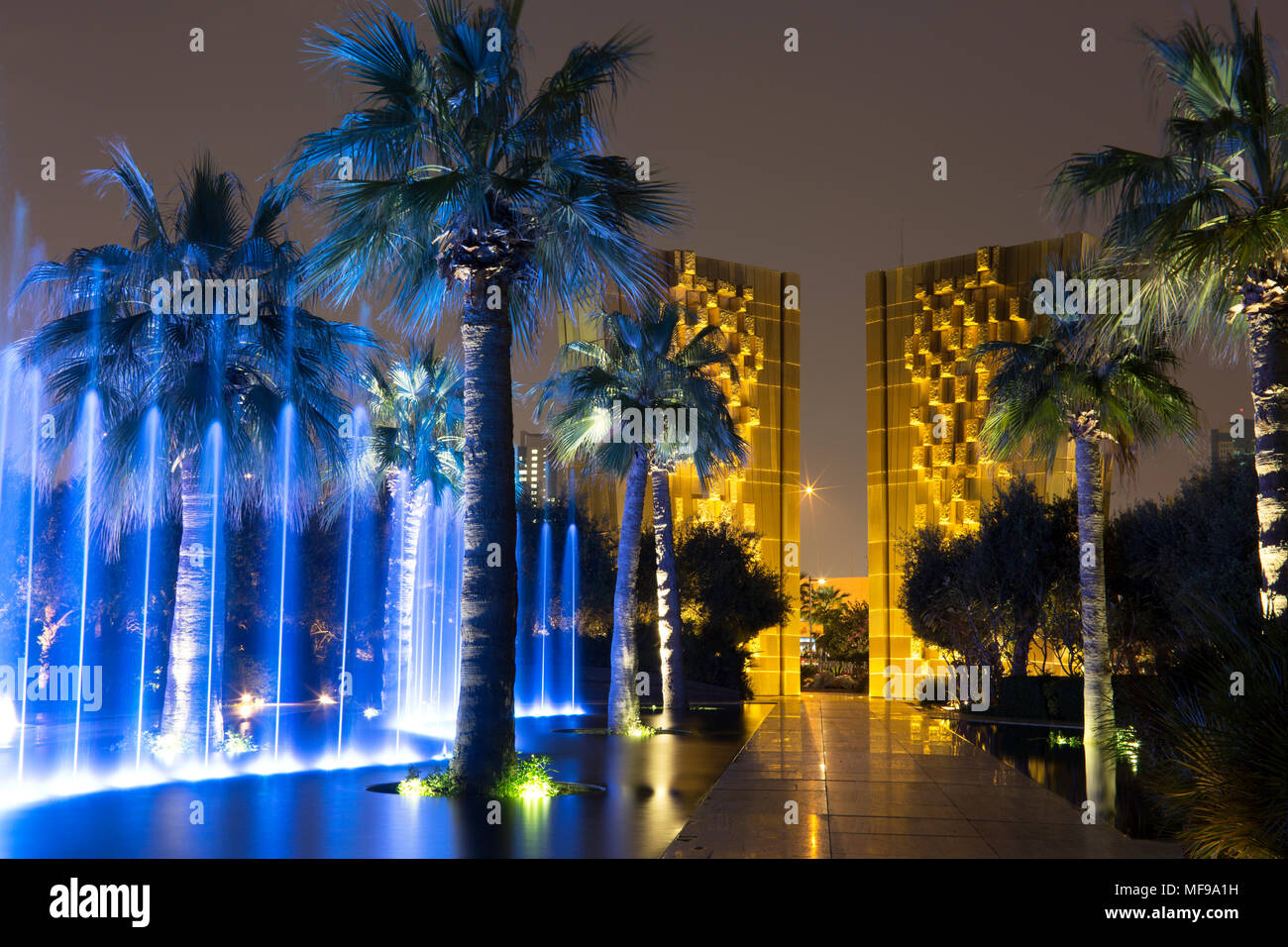 Al Shaheed Park, il Kuwait. Tempo di notte fontana spettacolo di luci. Costituzione monumento in background. Foto Stock