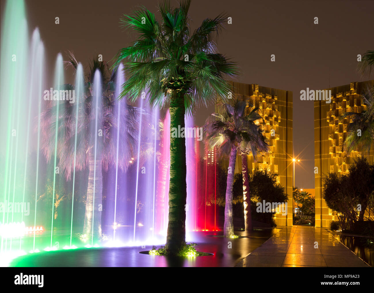 Al Shaheed Park, il Kuwait. Tempo di notte fontana spettacolo di luci. Costituzione monumento in background. Foto Stock