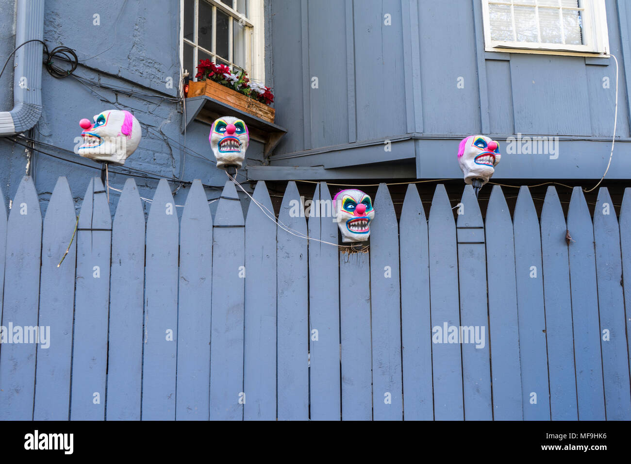 Maschere da clown in una recinzione Foto Stock