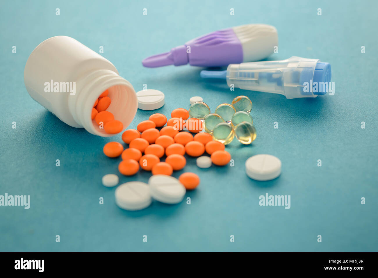 Una composizione di compresse di diverso genere e lancette, adulti e bambini su uno sfondo blu. Il trattamento della malattia. esame del sangue Foto Stock