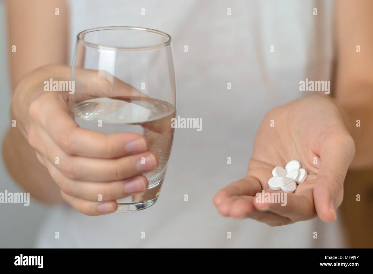 Closeup donna mano con le pillole medicina compresse e bicchiere di acqua per il mal di testa di trattamento. Sanitario, medico supplementi concept Foto Stock