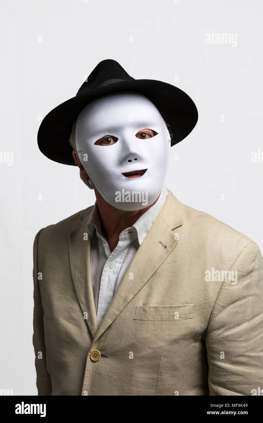 L'uomo bianco che indossa la maschera per il viso, black hat, e camicia di lino contro uno sfondo bianco Foto Stock