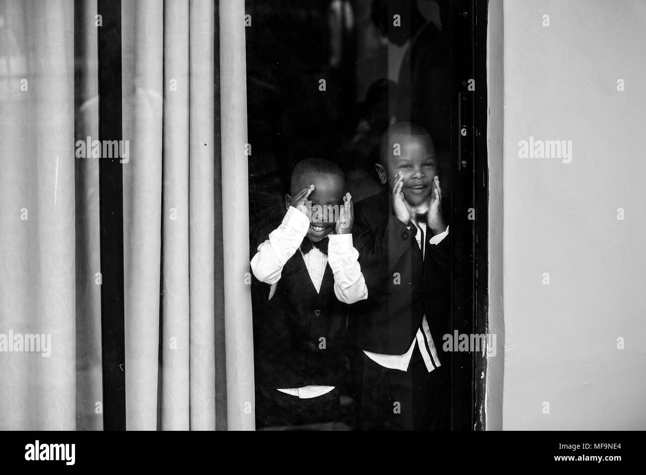 Due americano africano ai bambini di guardare attraverso una finestra Foto Stock
