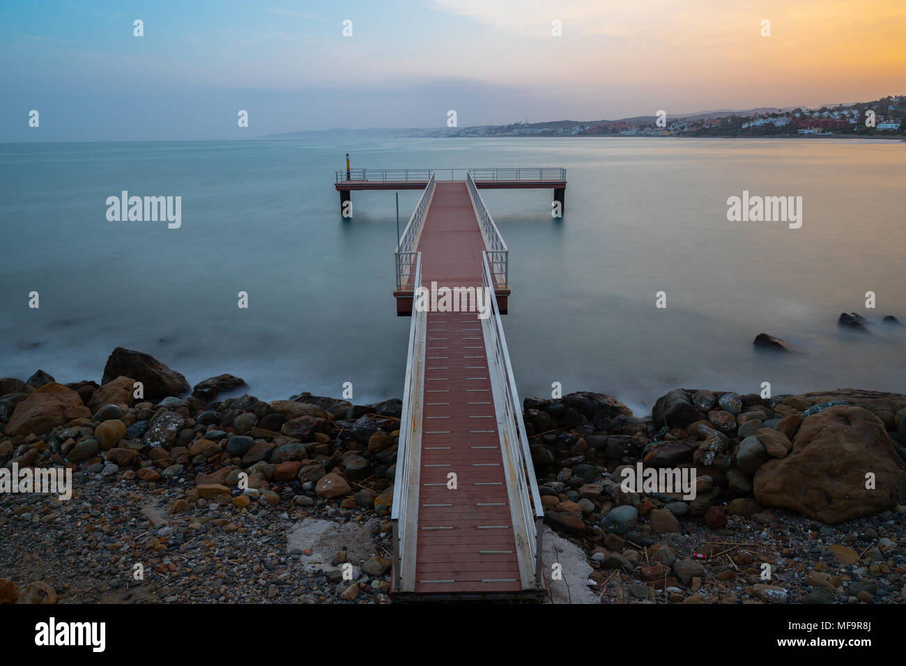 Una lunga esposizione di un molo presa al tramonto in Estepona un piccolo paese di pescatori sulla Costa del Sol in Spagna. Foto Stock