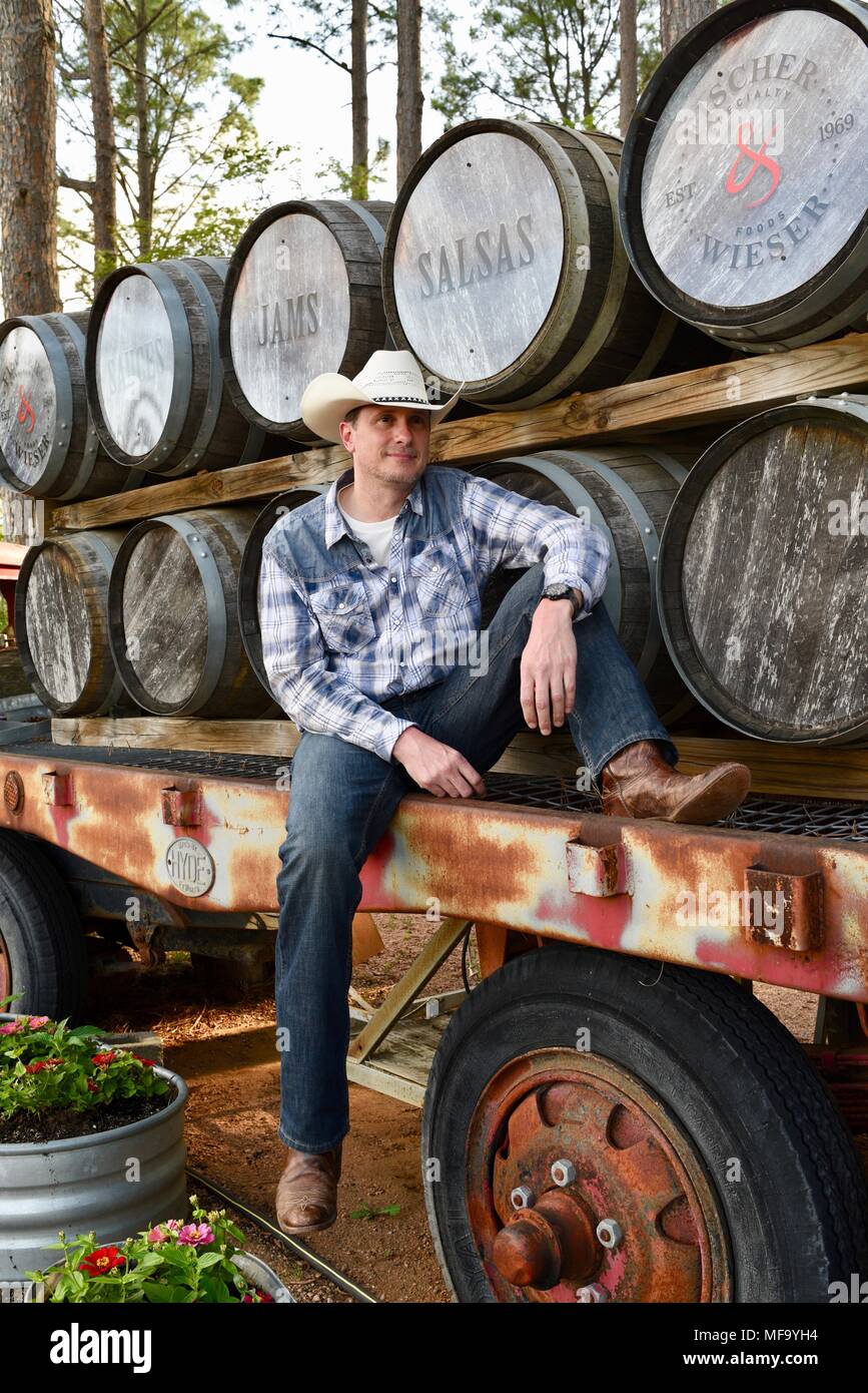 Western cowboy seduti sul rimorchio dello scanner a superficie piana con il whisky botti o barili a Pesche Das Haus, Fredericksburg, Texas, Stati Uniti d'America. Foto Stock