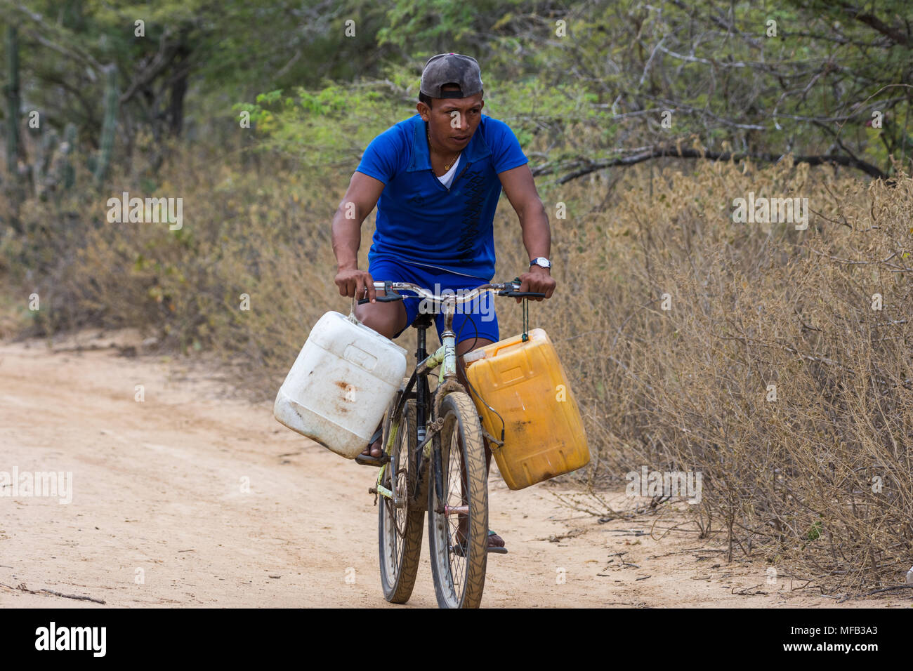 In zona rurale, un giovane corse una bicicletta per recuperare acqua con due grandi brocche d'acqua. La Colombia, Sud America. Foto Stock