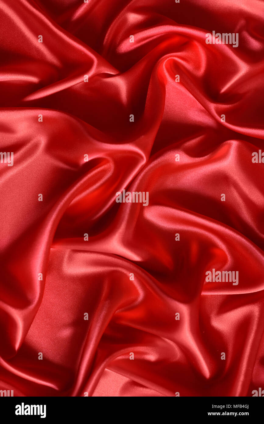 Close up di ondulazioni in rosso in tessuto di seta. In raso sfondo tessili. Foto Stock