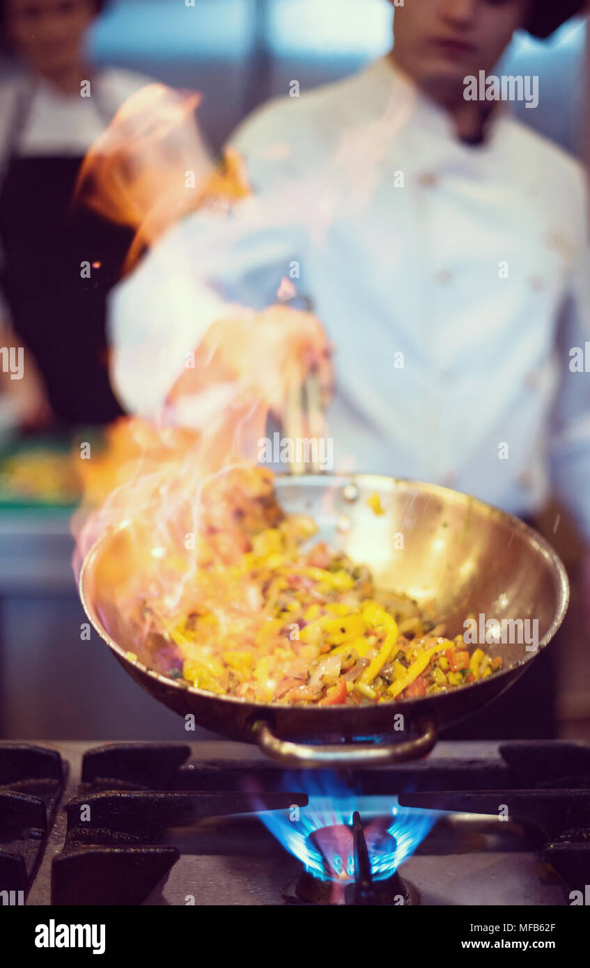 Chef di cucina e facendo flambe sul cibo del ristorante cucina Foto Stock