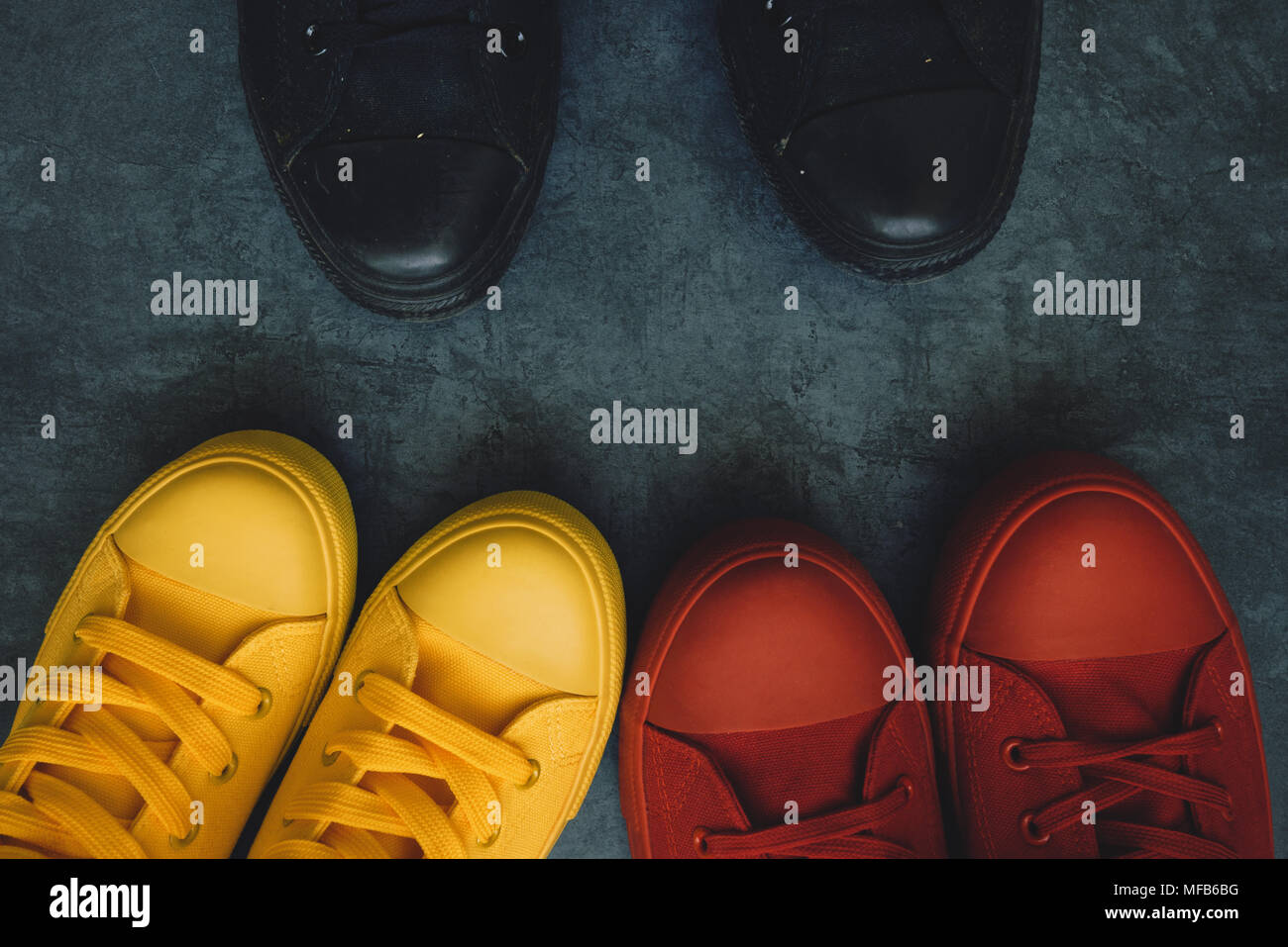 La gioventù il confronto immagine concettuale. I giovani in colorate sneakers di fronte una persona in nero scarpe casual. Foto Stock