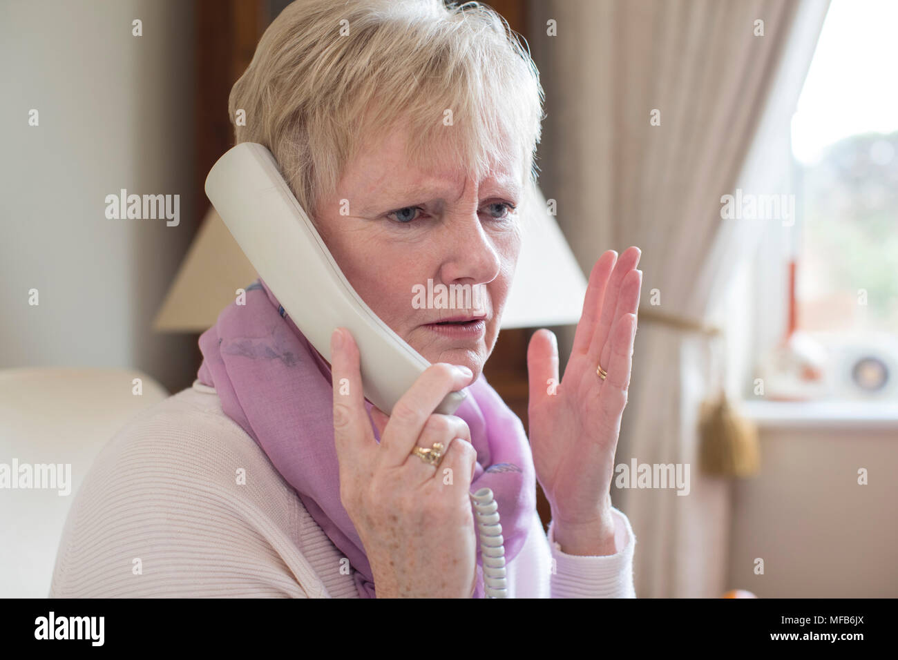Senior donna indesiderate di ricezione chiamata telefonica a casa Foto Stock
