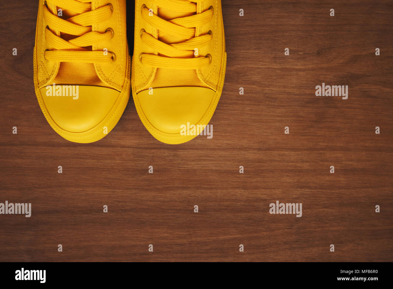 Elegante sneakers giallo su sfondo di legno dal di sopra con lo spazio di copia Foto Stock