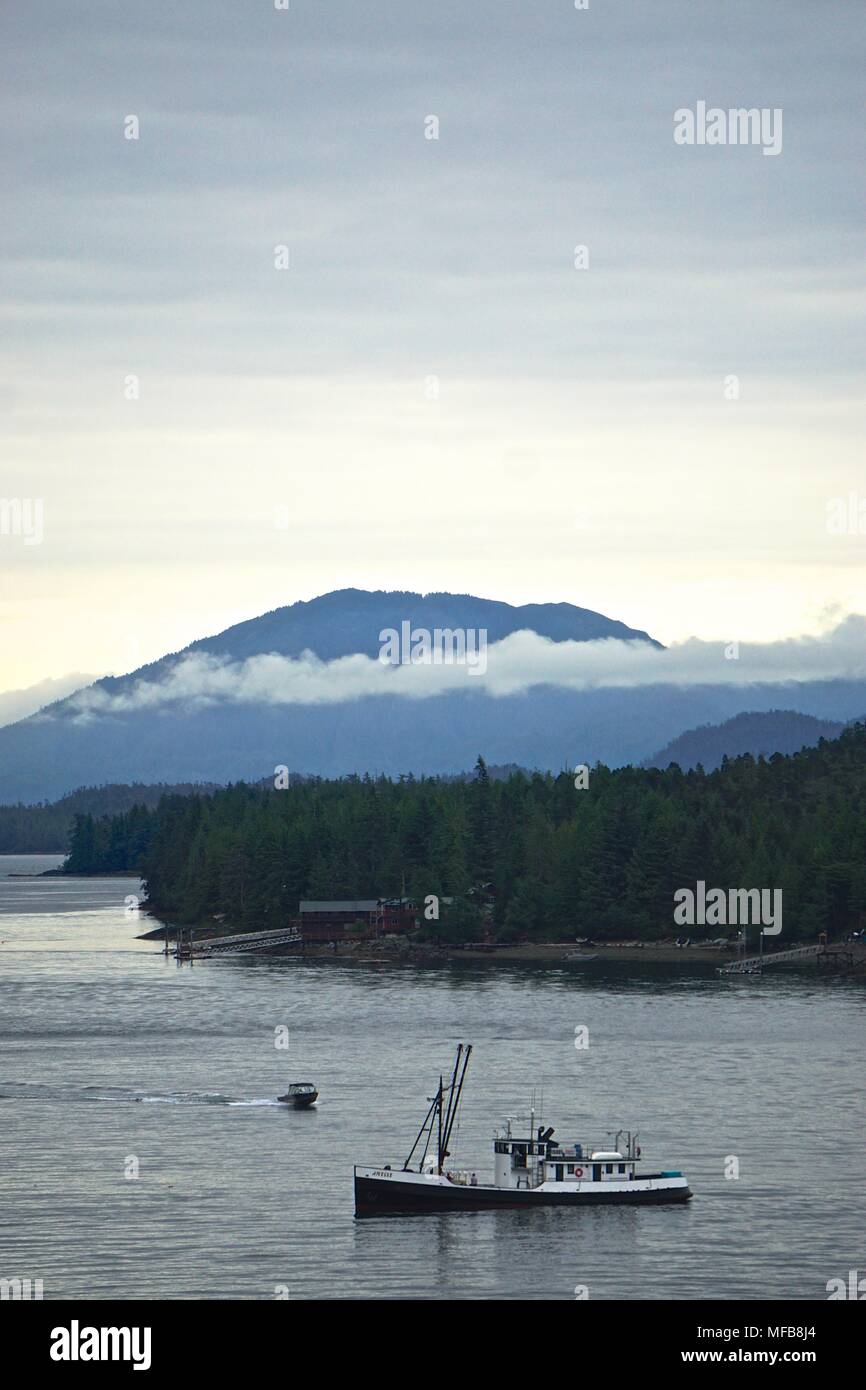 Ketchikan, Alaska: Una barca da pesca naviga lungo il Tongass Narrows sotto un cielo nuvoloso mattina, con le montagne sullo sfondo. Foto Stock