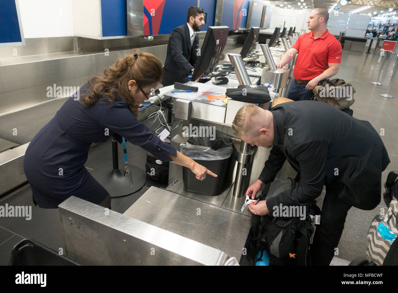Biglietto aereo agent incarica i passeggeri sul collocamento di tag su bagagli. Minneapolis St Paul Aeroporto Internazionale Minneapolis Minnesota MN USA Foto Stock