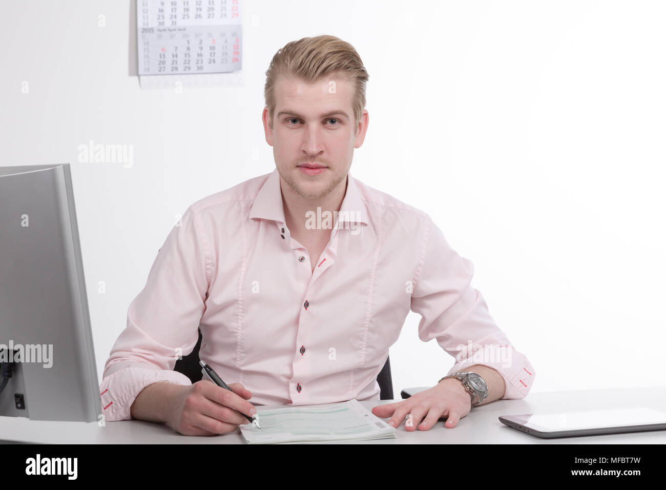 Giovane uomo che lavora alla reception sul lavoro della carta Foto Stock