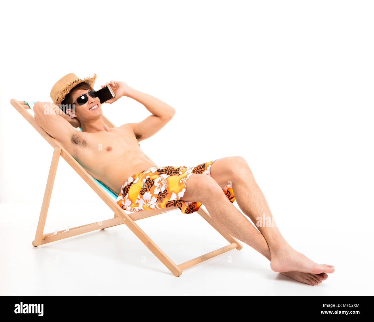 Rilassata uomo seduto nella sedia sdraio e parlando al telefono Foto Stock