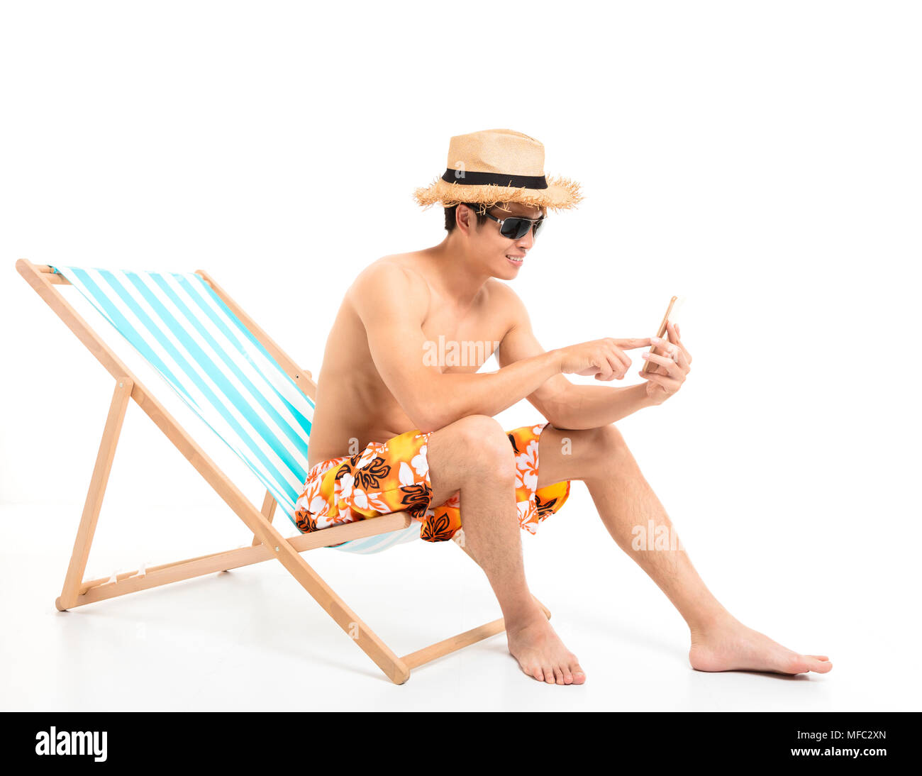 Rilassata uomo seduto nella sedia sdraio e utilizzando il telefono Foto Stock