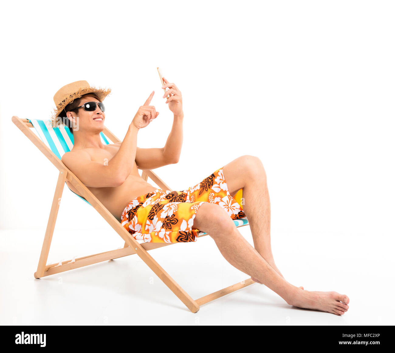 Rilassata uomo seduto nella sedia sdraio e utilizzo di smart phone Foto Stock