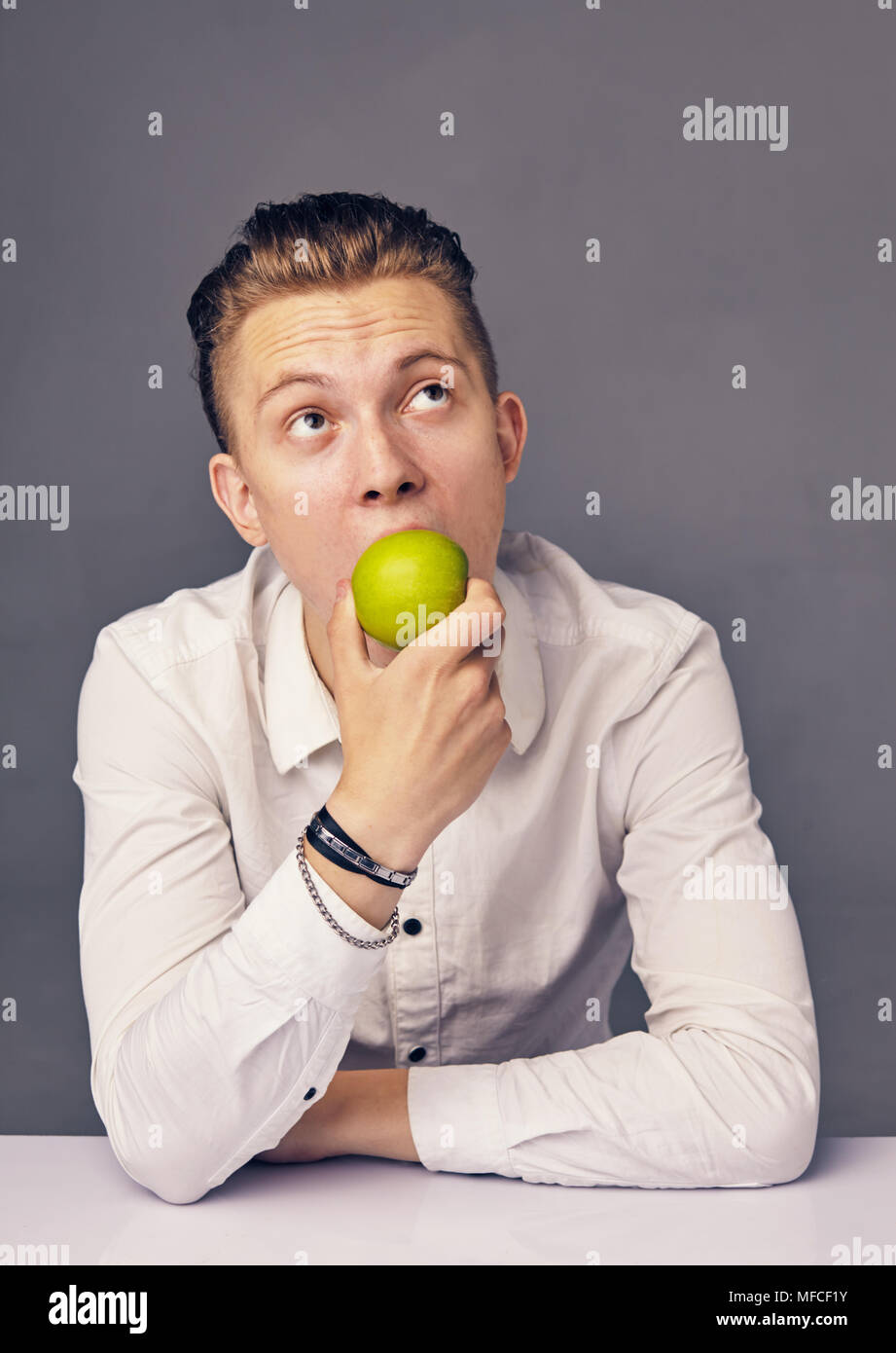 L'uomo mangiare apple, contro uno sfondo scuro Foto Stock