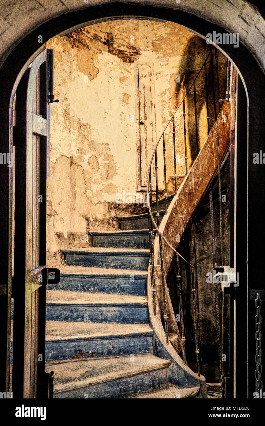 Una immagine composita che mostra la vista attraverso una porta a una misteriosa ombra scendendo una scala abbandonati. Foto Stock