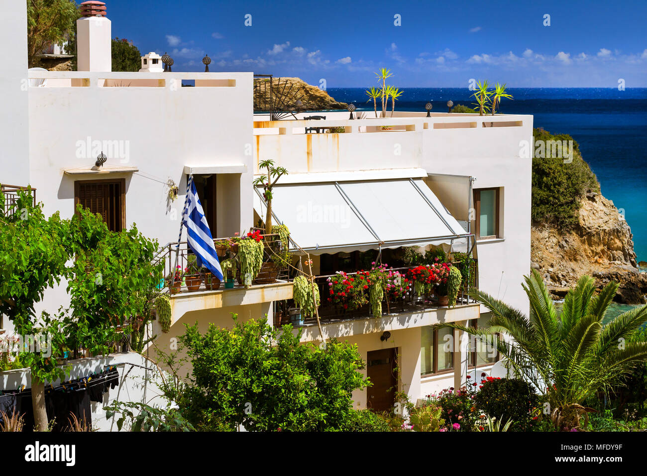 Moderno e classico resort architettura Greca, bianco edificio sorge sulla riva del mare cretese. Bandiera Greca è impostato sulla facciata dell'edificio. Resort vi Foto Stock
