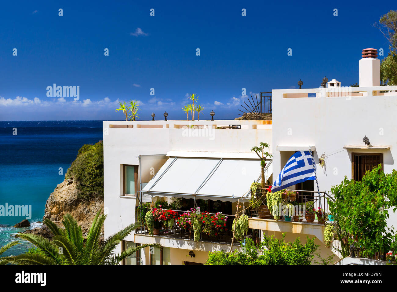 Moderno e classico resort architettura Greca, bianco edificio sorge sulla riva del mare cretese. Bandiera Greca è impostato sulla facciata dell'edificio. Resort vi Foto Stock
