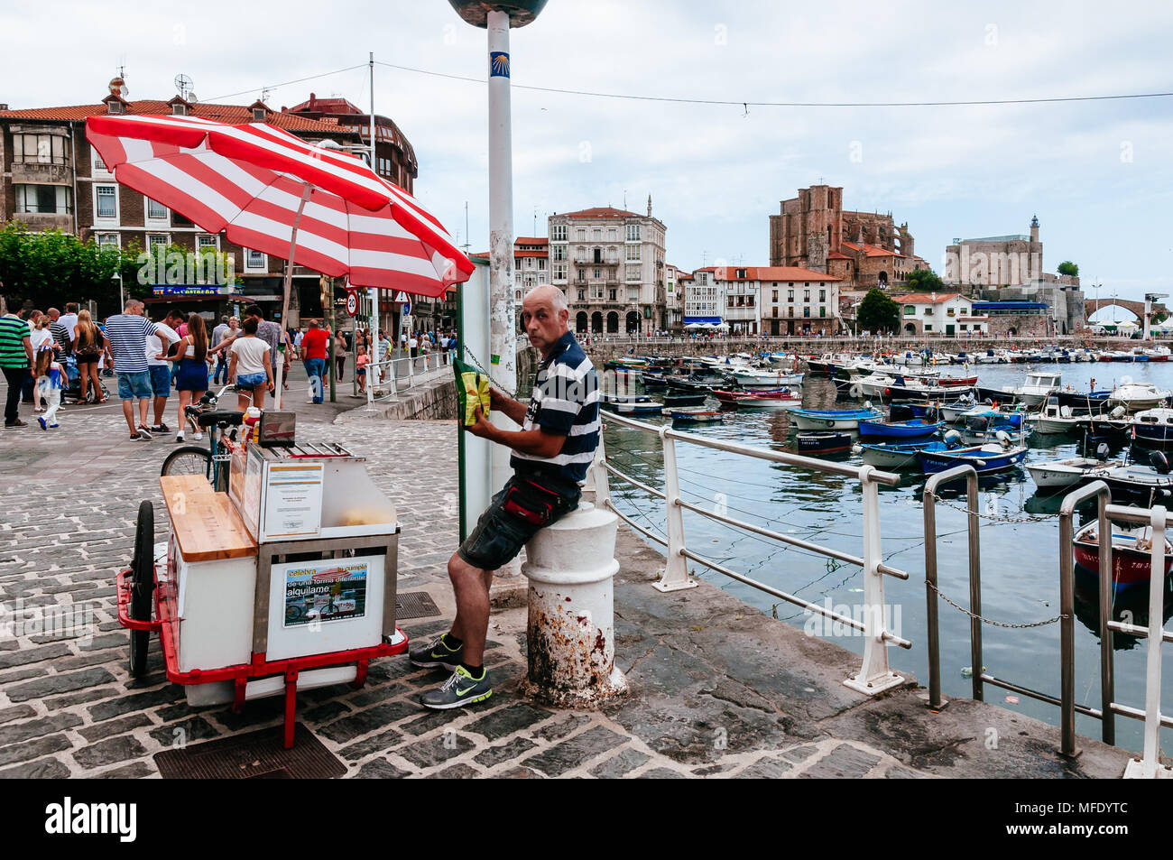 Hot Dog bancarella di strada presso il lungomare con il porto di Santa María de la Asunción chiesa, il faro del Castello di Santa Ana e il ponte medievale Foto Stock