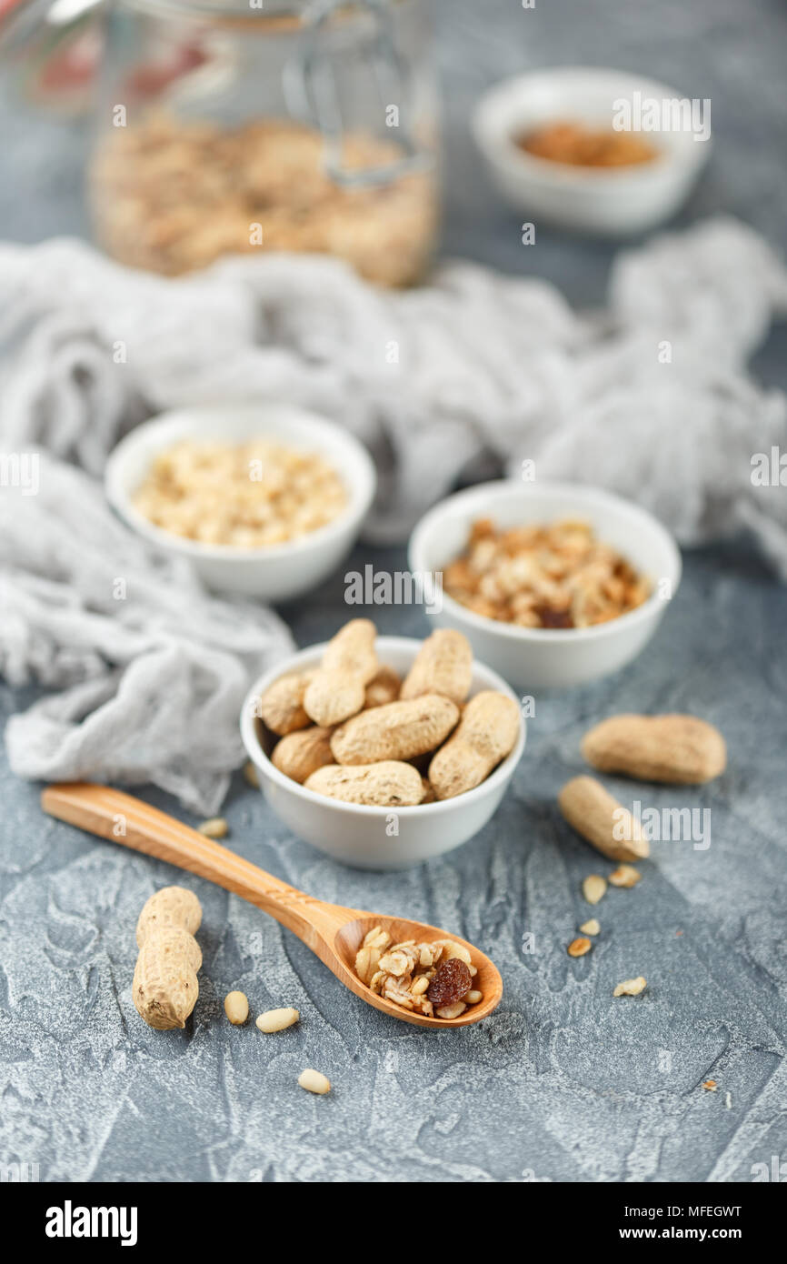 Set di diversi tipi di dadi - Arachidi in guscio, pinoli e muesli fatti in casa in un barattolo di vetro su uno sfondo grigio Foto Stock