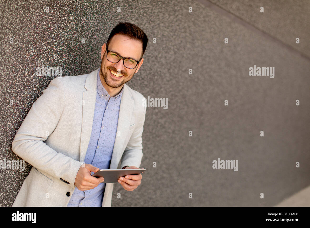 Ritratto di un giovane imprenditore azienda digitale compressa all'aperto in ambiente urbano Foto Stock