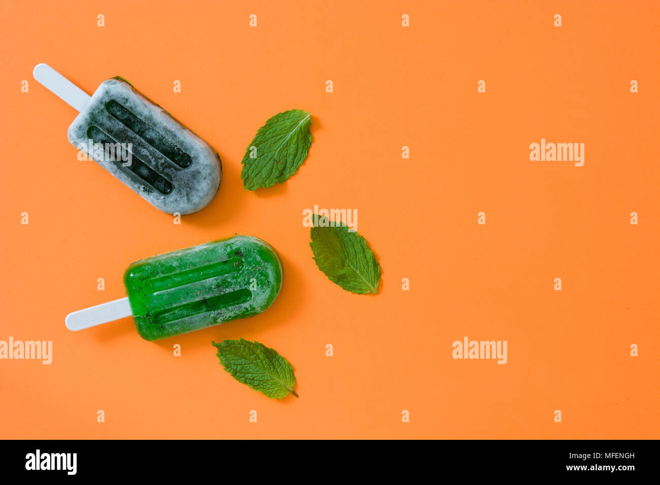 Verde popsicles congelate su sfondo arancione. Vista superiore Foto Stock