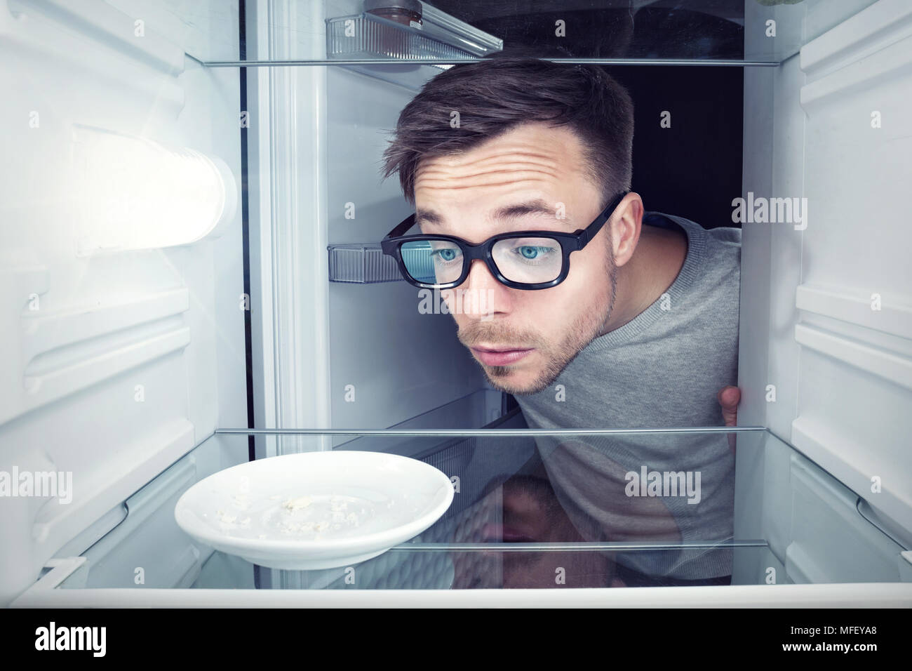 Studente cerca all'interno di un frigorifero vuoto Foto Stock
