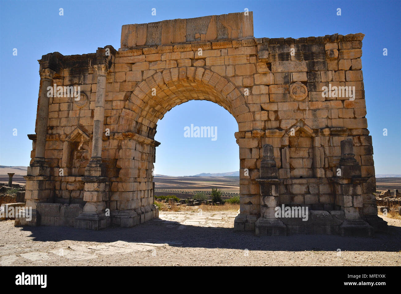 Scenic vista frontale dell'arco trionfale dedicato all'imperatore Caracalla a Volubilis rovine romane (Fès-Meknès, Marocco) Foto Stock