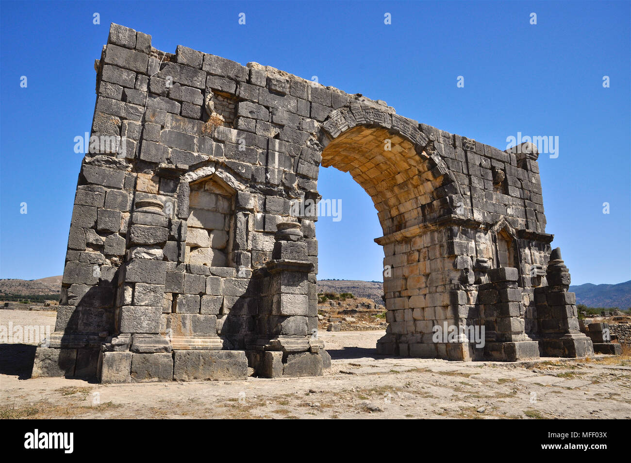 Scenic vista posteriore dell'arco trionfale dedicato all'imperatore Caracalla a Volubilis rovine romane (Fès-Meknès, Marocco) Foto Stock