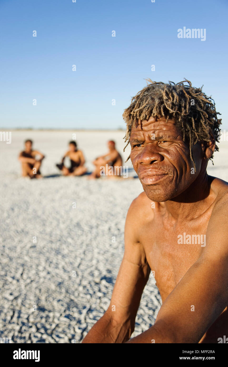 I Boscimani vestiti di pelli tradizionali, seduti in un semicerchio sull'essiccato fino Makgadikgadi padelle la riproduzione di un gioco tradizionale, Data: 18.12.2008 Ref: Z Foto Stock