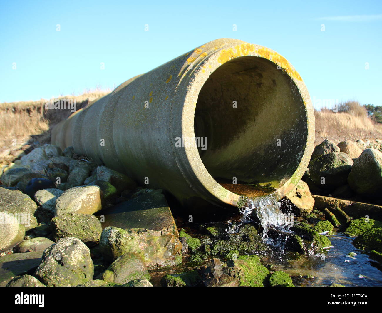 Calcestruzzo di cemento grigio tubo di scarico con il flusso di acqua Foto Stock