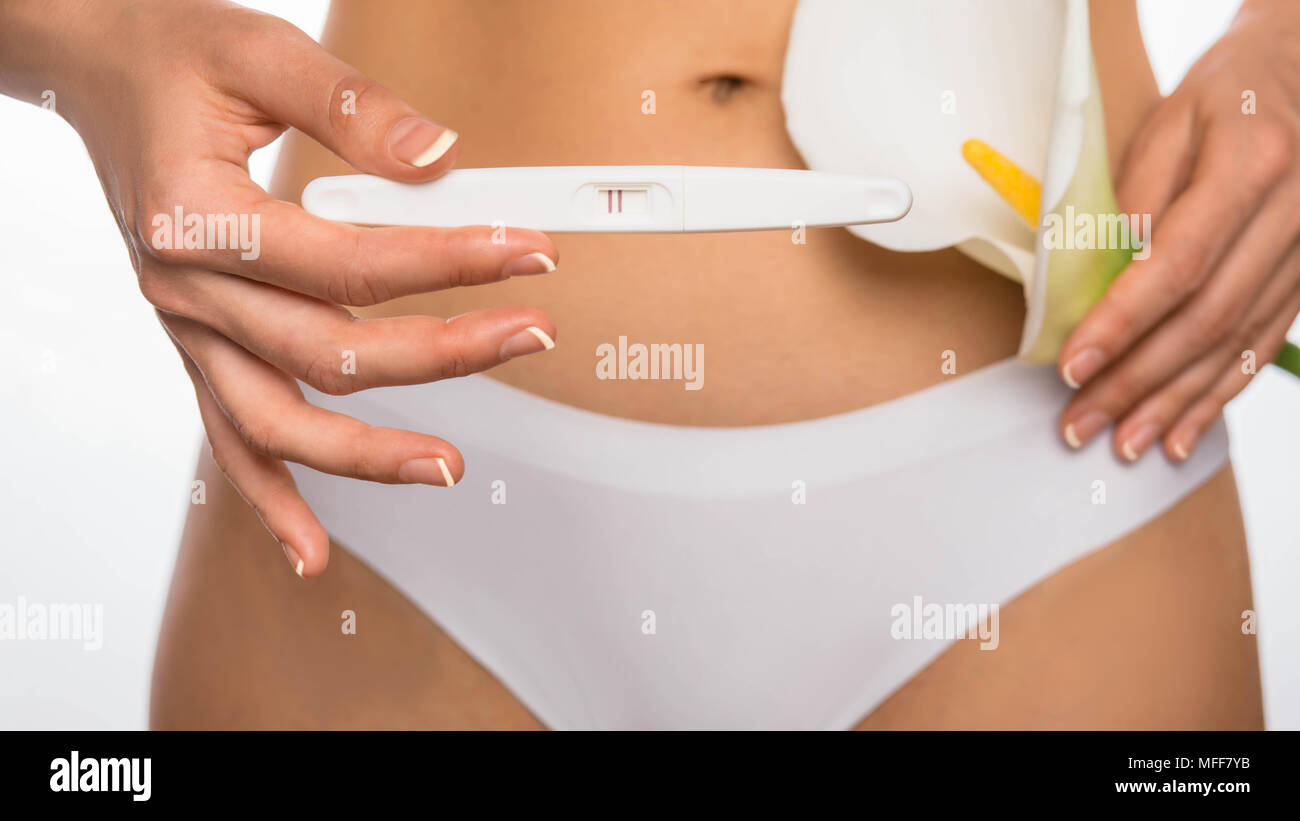 Positivo al test di gravidanza contro un stomaco Foto Stock