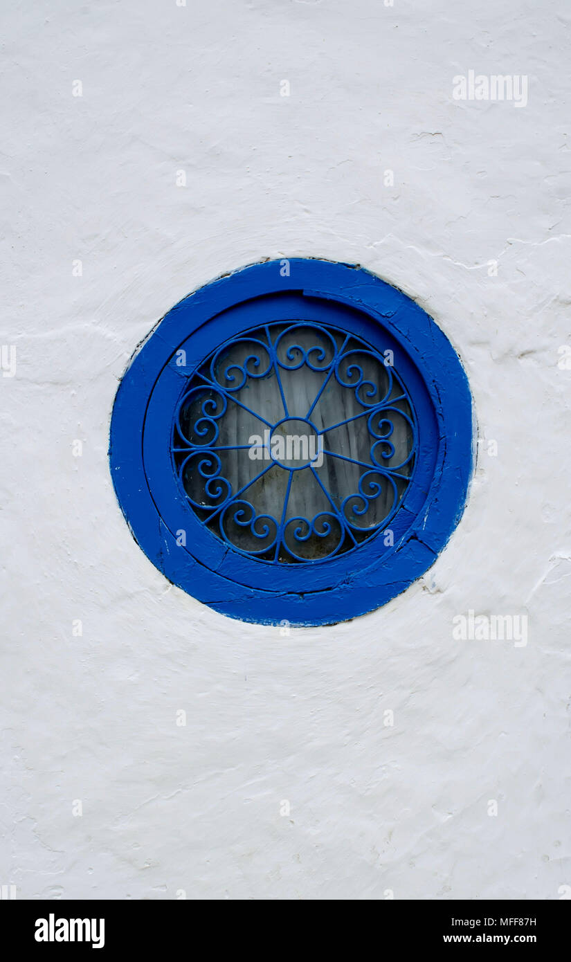 Finestra rotonda con una cornice blu con una griglia modellato su una parete bianca in Tunisia Foto Stock