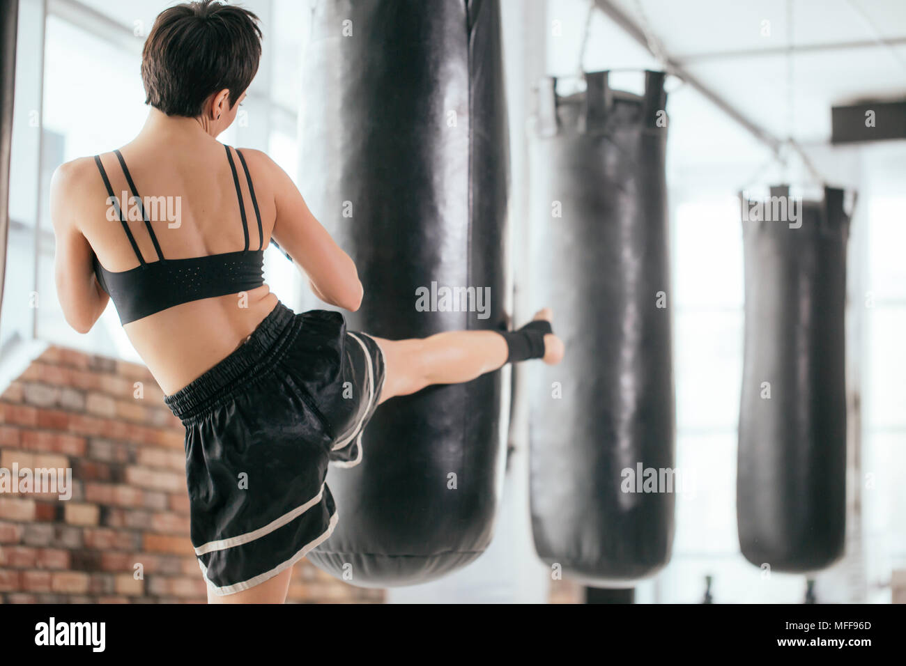 Vista posteriore della fotografia di donna giovane atleta calci boxe in gomma. gambe forti. Foto Stock