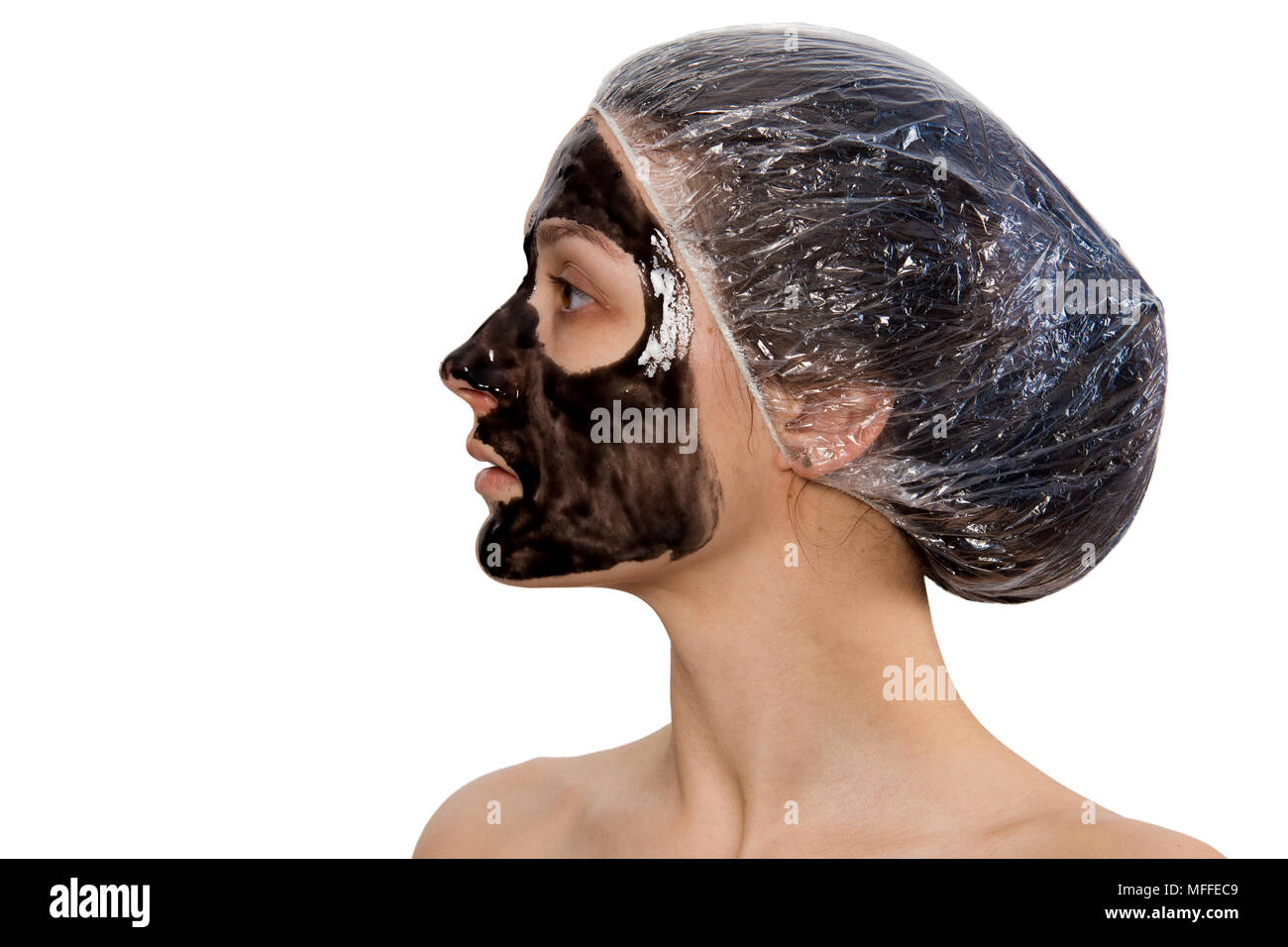 Profilo di donna ritratto con buccia di colore nero-off maschera sul volto isolato su sfondo bianco. Bellezza della pelle e la cura del tema. Foto Stock
