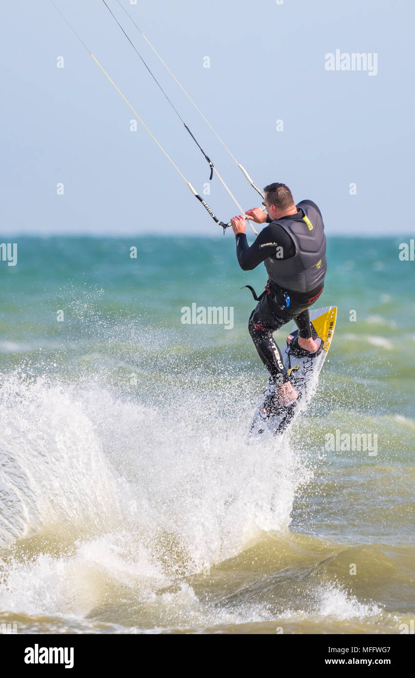 Uomo di Kitesurf in mare e prendendo il largo lasciando uno spruzzo d'acqua. Kitesurfer eseguendo uno stunt. Ritratto Foto Stock