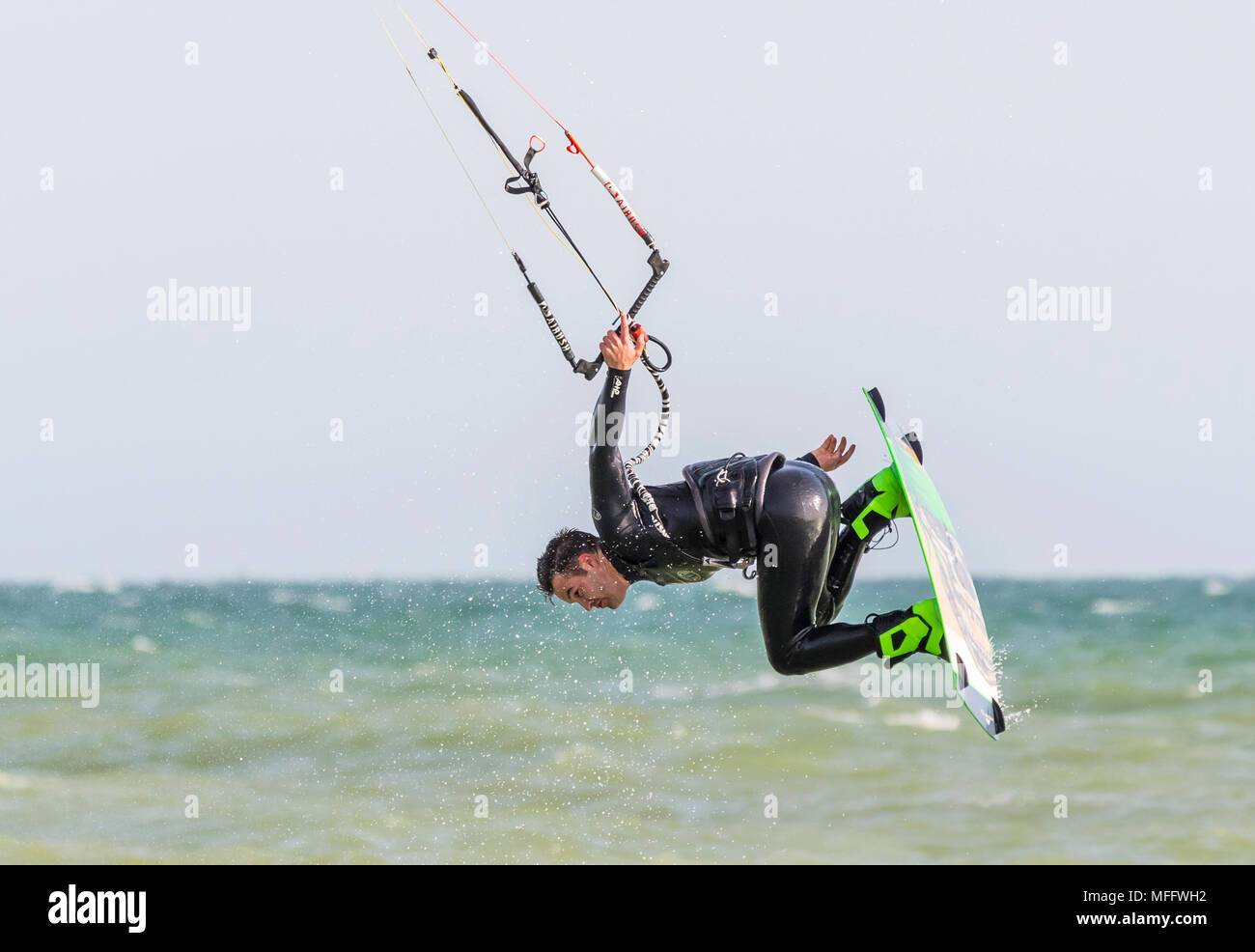 Uomo di Kitesurf in mare mentre in aria in un testacoda, tenendo con una mano. Kitesurfer sull'oceano. Foto Stock