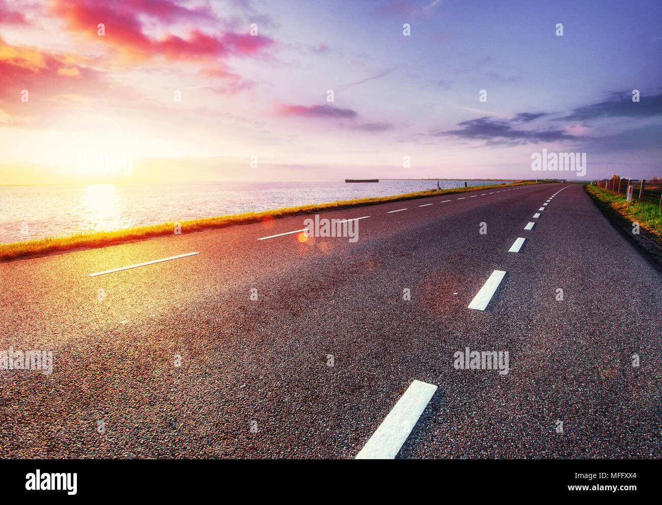 Strada asfaltata lungo il mare al tramonto Foto Stock