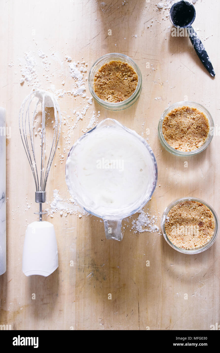 Preparazione di una cheesecake su jar senza cottura, biscuit mescolato con burro sono pressati nel contenitore in vetro Foto Stock