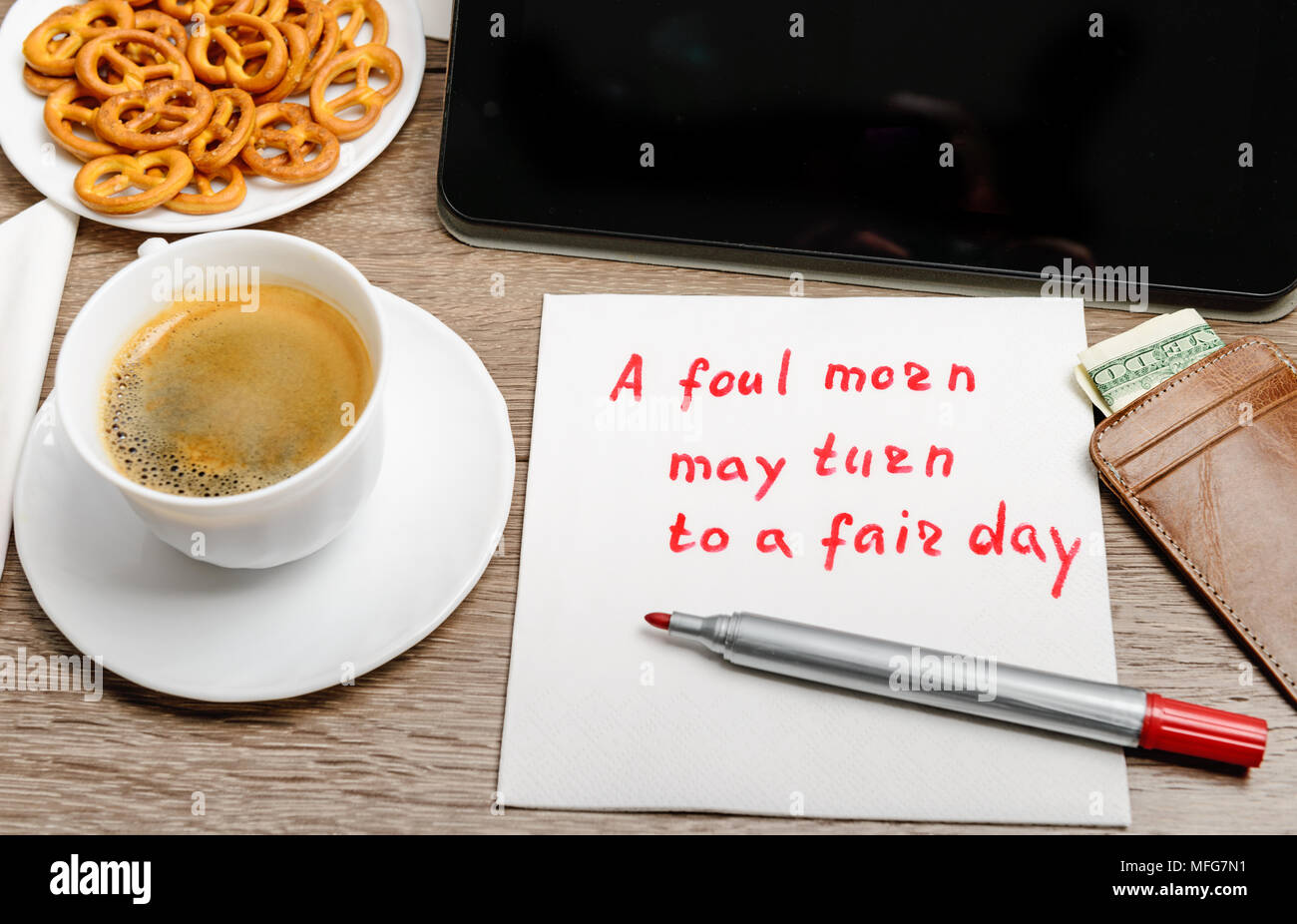 Tovagliolo proverbio del messaggio sul tavolo di legno con caffè, alcuni alimenti e tablet PC un fallo mattino può ruotare per un giorno di fiera Foto Stock