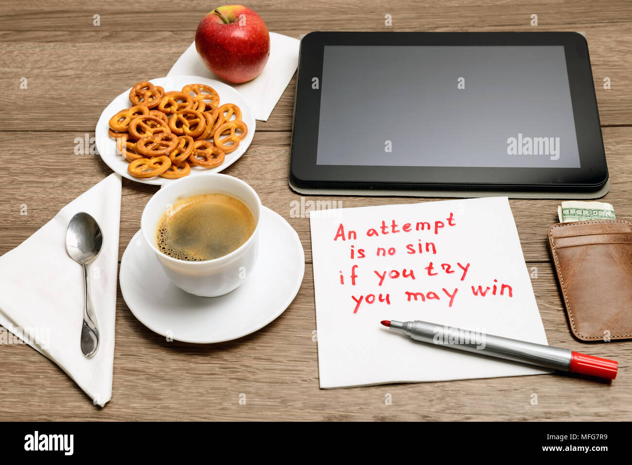 Tovagliolo scrittura proverbio del messaggio sul tavolo di legno con caffè, alcuni alimenti e tablet PC un tentativo è senza peccato - se si prova che si può vincere Foto Stock