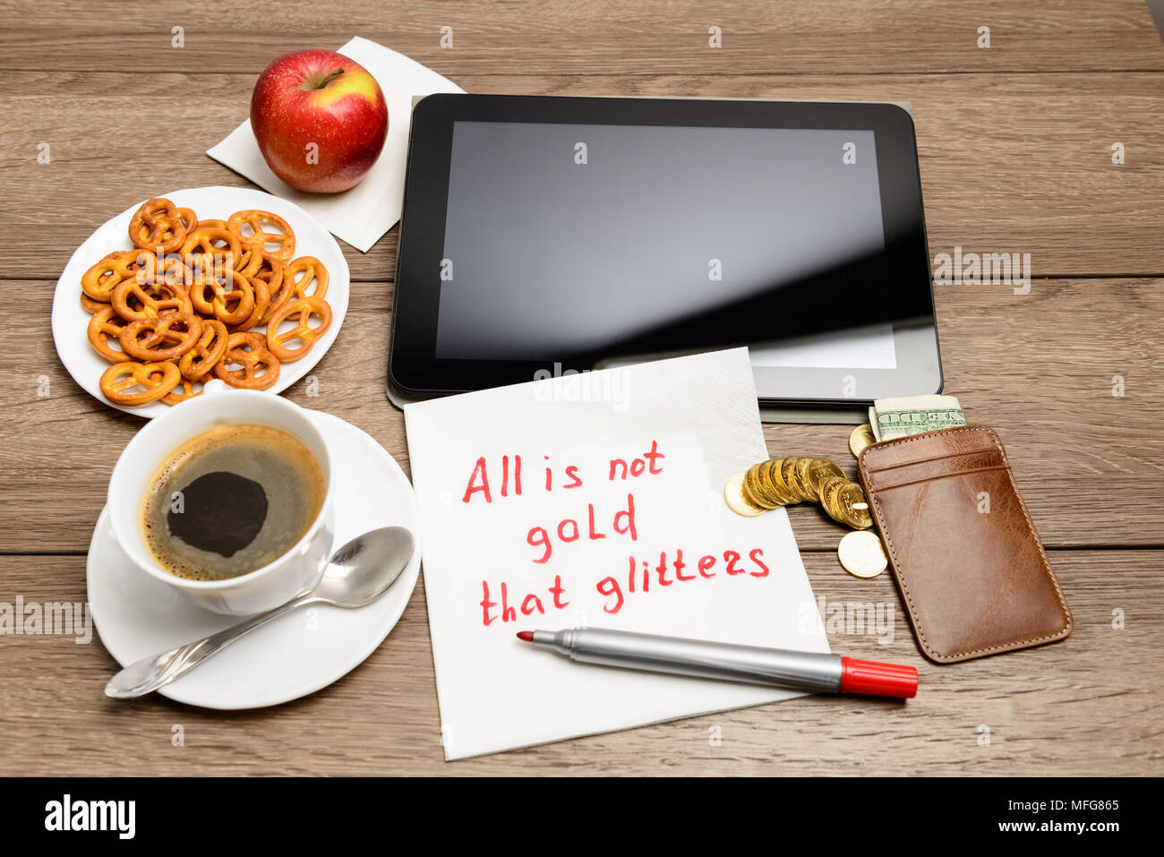 Tavolo in legno con caffè, alcuni prodotti alimentari e igienico proverbio del messaggio non è tutto oro quello che luccica Foto Stock