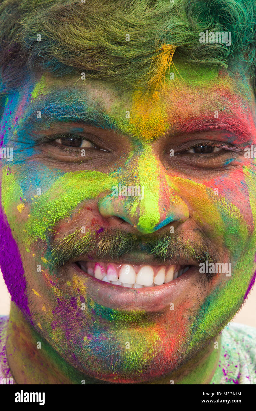 Uomo sorridente con faccia vernice, Holi festival, Mumbai, India Foto Stock