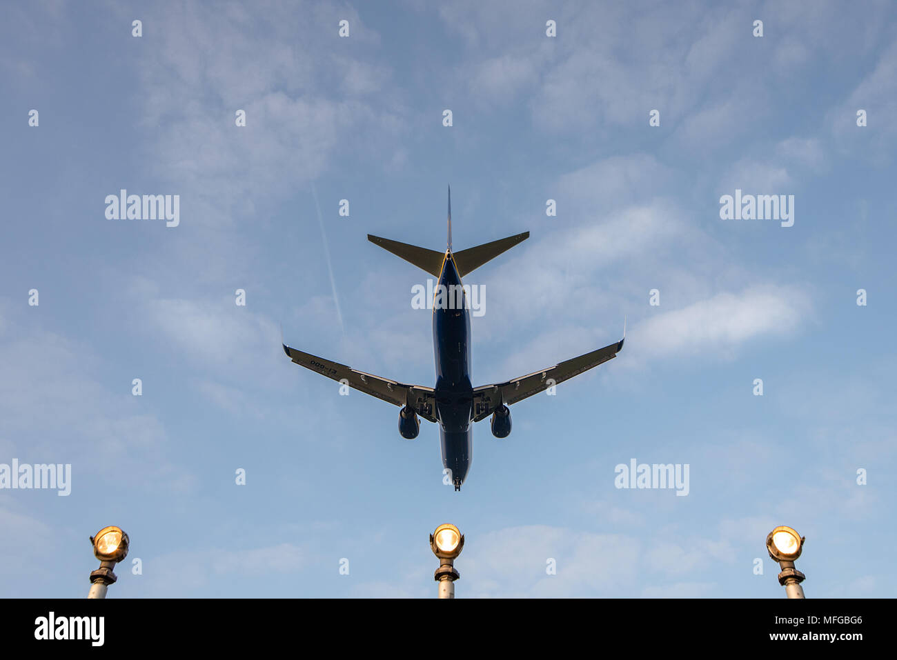 Un atterraggio aereo commerciale volando sopra la testa in arrivo a terra con la pista delle luci di atterraggio contro il cielo blu. Foto Stock