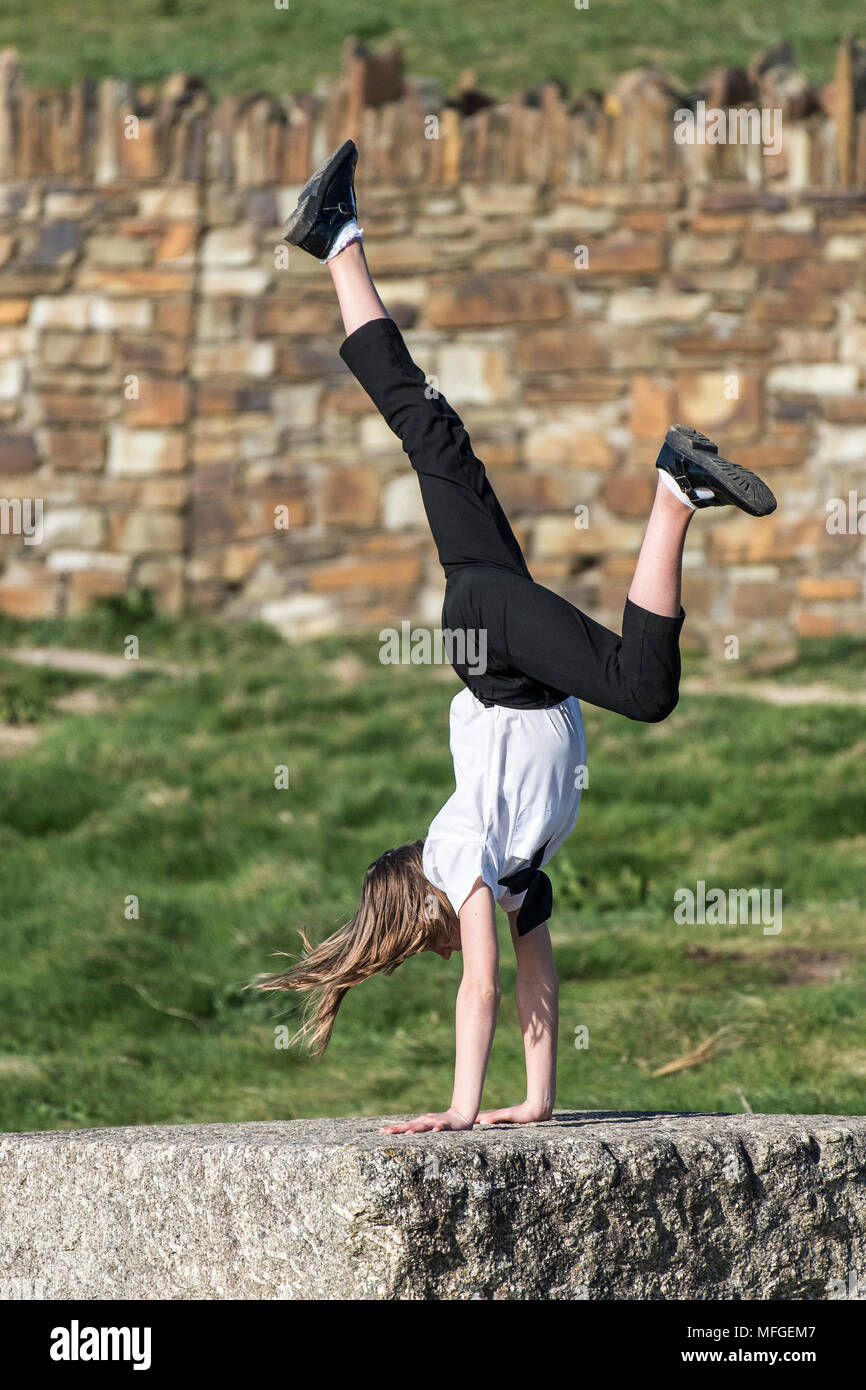 Un giovane adolescente di eseguire un handstand su un blocco di granito. Foto Stock