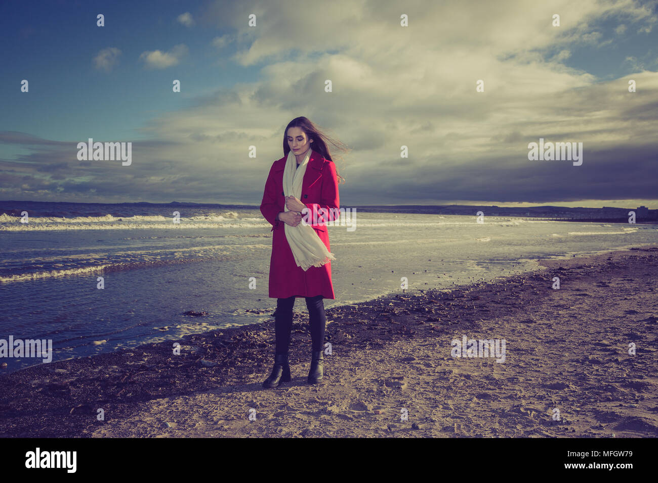Donna in giacca rossa su una spiaggia. Foto Stock